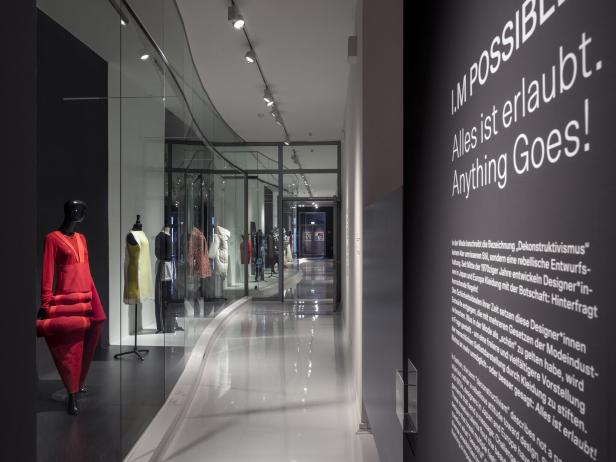 Ein Ausstellungsraum mit Kleidern auf Schaufensterpuppen und einem Schild mit der Aufschrift „Alles ist erlaubt“.