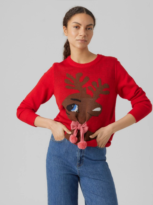 Eine Frau trägt einen roten Weihnachtspullover mit einem Rentier-Motiv von Vero Moda.