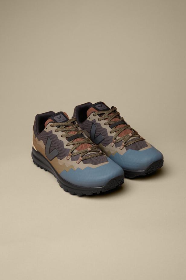 Ein Paar Veja-Sneakers in Blau-, Braun- und Grautönen stehen vor einem beigen Hintergrund.