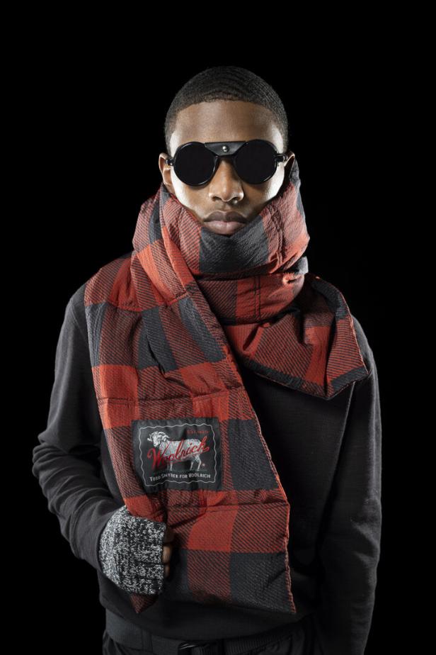 Ein Mann mit runder Sonnenbrille und einem rot-schwarzen Schal von Woolrich.