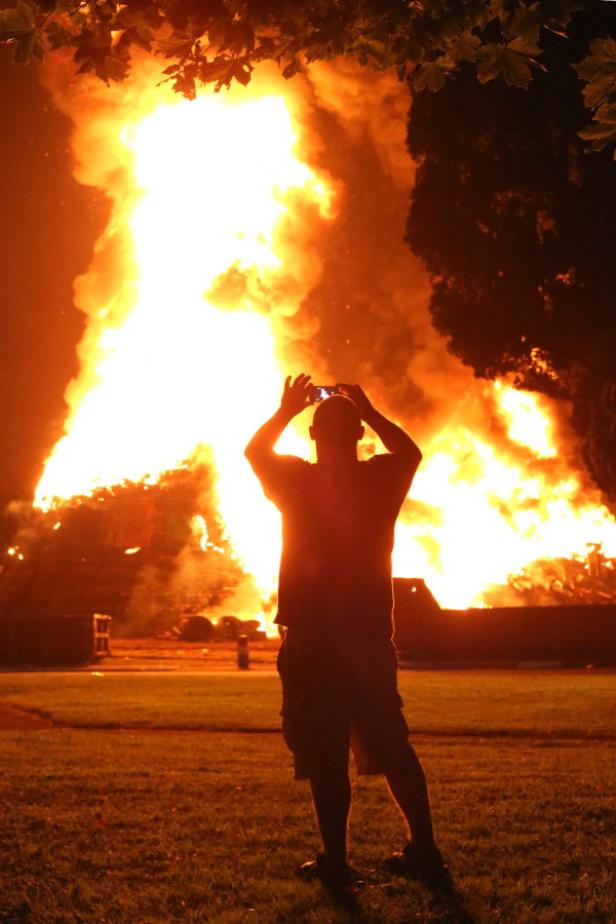 Eine Person fotografiert ein großes Feuer mit ihrem Smartphone.