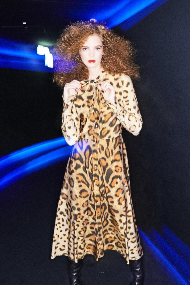 Eine Frau mit lockigem Haar trägt ein Kleid von Oscar de la Renta bei Popp & Kretschmer.