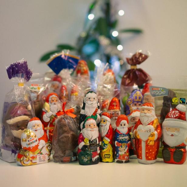 Eine Sammlung von Schokoladen-Weihnachtsmännern verschiedener Marken steht auf einem Tisch.