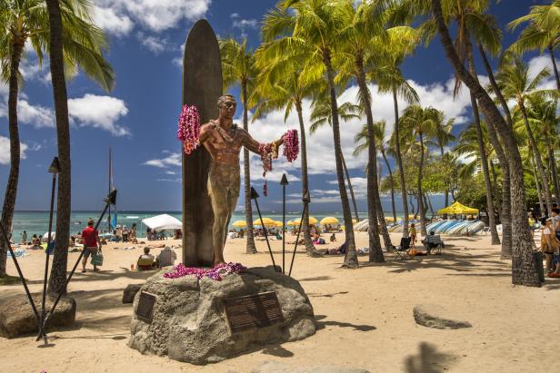 Eine Statue von Duke Kahanamoku mit Blumenkränzen am Waikiki Beach, Honolulu.