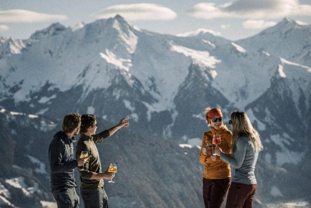 Drei Personen stehen auf einem Berggipfel und blicken auf schneebedeckte Berge in der Ferne: Skifahren im Zillertal