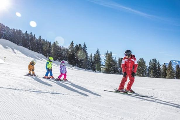 Eine Gruppe von Kindern fährt Ski auf einer Piste und genießt den Winterspaß in der Natur: Skischulen im Zillertal für Groß und Klein