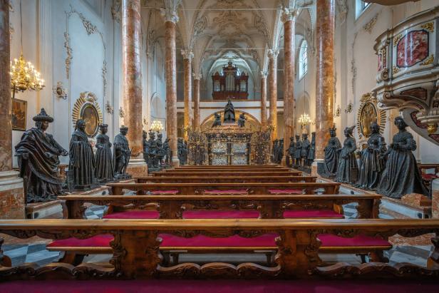 Blick in das Innere der Hofkirche in Innsbruck mit Statuen und Kirchenbänken.