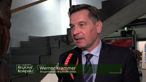 Ein Mann im Anzug wird vor einer Treppe interviewt.