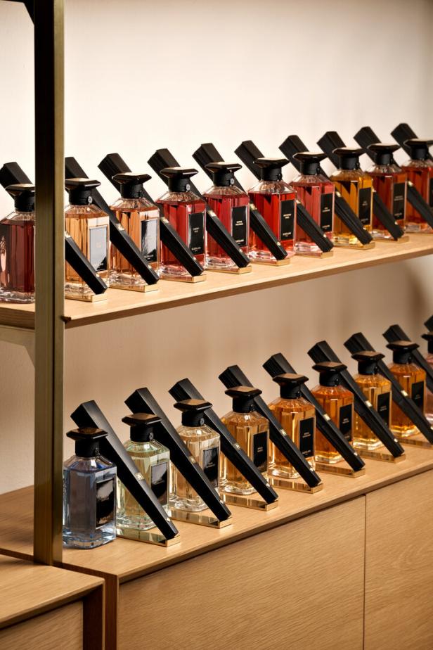 Eine Reihe von Guerlain-Parfümflaschen unterschiedlicher Farben stehen auf Holzregalen.