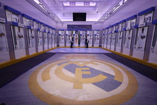 Blick in die Umkleidekabine von Real Madrid mit dem Vereinslogo auf dem Boden.
