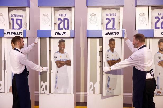 Zwei Männer in Uniform präsentieren die Umkleidekabinen der Real Madrid-Spieler D. Ceballos, Viní Jr., Rodrygo und Isco.