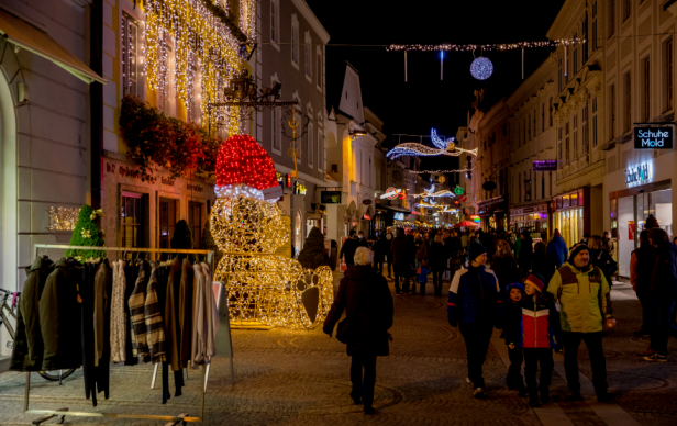 Eine weihnachtlich beleuchtete Einkaufsstraße mit einem Schneemann.