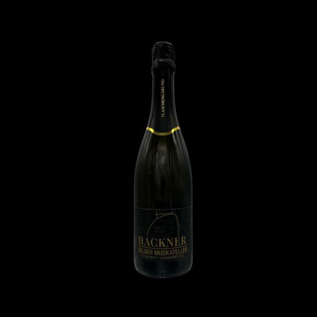 Eine Flasche „Hackner Gelber Muskateller Extra Brut“ Sekt vor schwarzem Hintergrund.