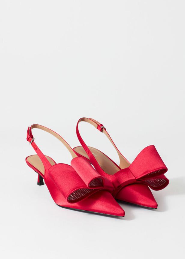 Ein Paar rote Slingpumps mit Schleifenverzierungen stehen auf einem weißen Hintergrund.
