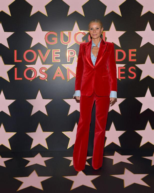 Gwyneth Paltrow trägt einen roten Samtanzug vor einer Wand mit Sternen und dem Schriftzug „Gucci Love Parade Los Angeles“.