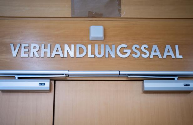 Über einer Holztür steht in großen silbernen Buchstaben das Wort „Verhandlungssaal“.