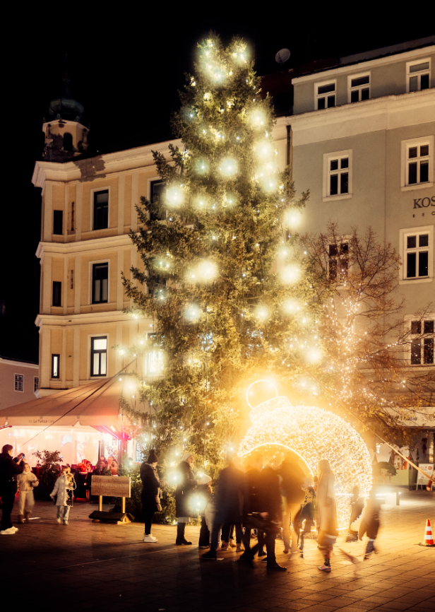 Ein beleuchteter, riesiger Weihnachtsbaum in einer Fußgängerzone.