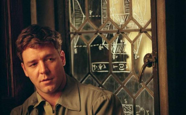 Russell Crowe steht vor einem Fenster mit mathematischen Formeln.