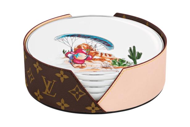 Ein Louis Vuitton Untersetzer-Set mit einer Wüstenlandschaft und einer Cartoon-Figur am Fallschirm.