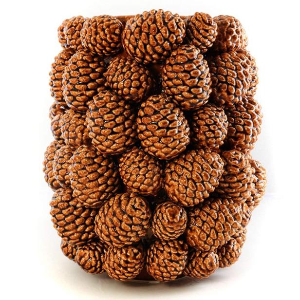 Eine Vase, die vollständig mit braunen Tannenzapfen bedeckt ist.
