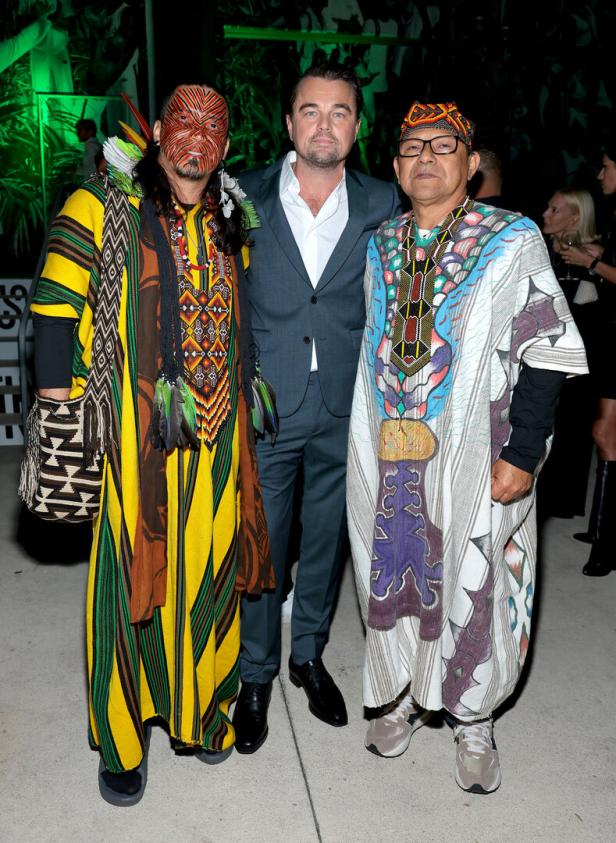 Leonardo DiCaprio posiert mit zwei indigenen Führern für ein Foto.