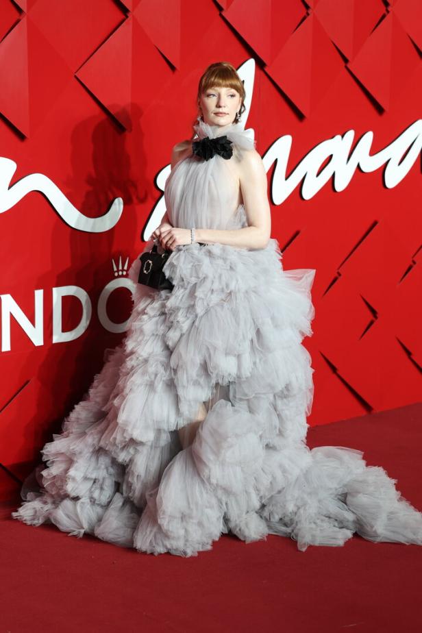 Florence Pugh in einem grauen Tüllkleid auf einem roten Teppich.