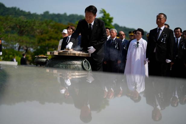 Südkoreas Präsident Yoon steht mit weißen Handschuhen vor einer Gedenkstätte.