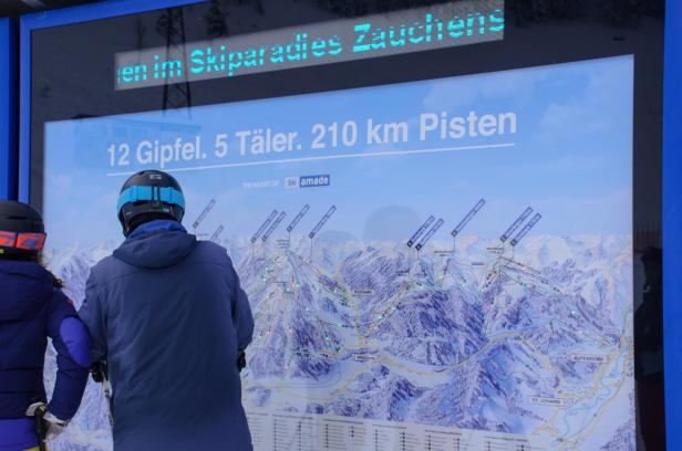 Skifahrer stehen vor einer Pistenkarte 