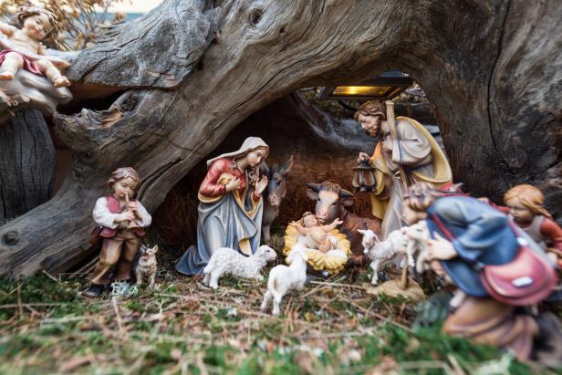 Eine Weihnachtskrippe mit Maria, Josef, dem Jesuskind und Hirten unter einem Baum.