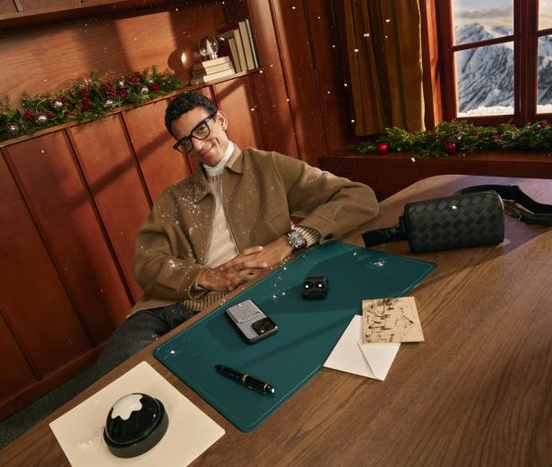 Ein Mann sitzt an einem Schreibtisch mit Montblanc-Produkten und Blick auf schneebedeckte Berge.