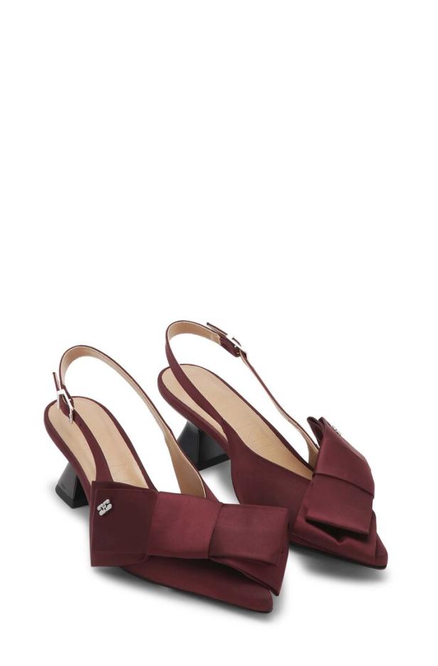 Ein Paar burgunderrote Slingpumps mit Schleifenverzierungen stehen auf einem weißen Hintergrund.