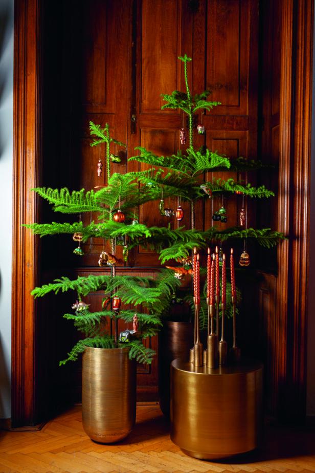 Ein geschmückter Tannenbaum steht neben einem goldenen Kerzenständer.