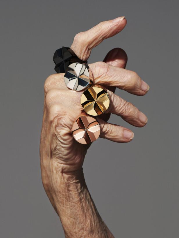 Eine Hand mit vier auffälligen, runden Ringen in Schwarz, Silber, Gold und Roségold.