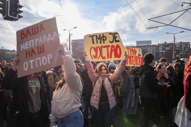 Students hold banners as they block the road for fifteen minutes to pay their respect for fifteen victims of a fatal roof collapse at Novi Sad's railway station, in Belgrade