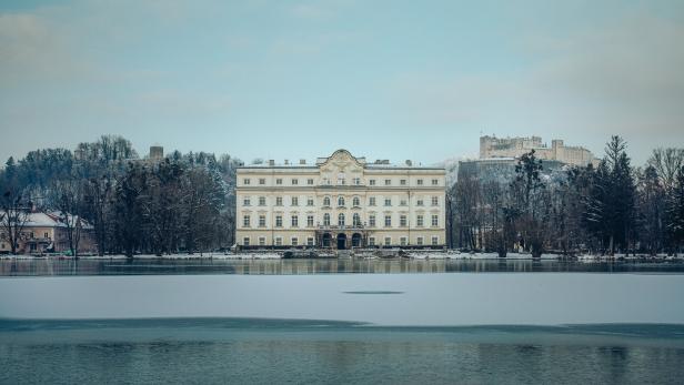 Schloss Leopoldskron vor einer teilweise zugefrorenen Wasserfläche.