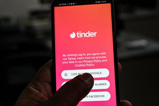 Ein Smartphone zeigt den Anmeldebildschirm der Dating-App Tinder.