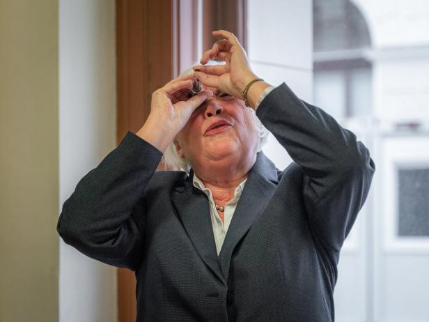 Vera Hammer hält einen Stein in die Höhe. Sie betrachtet ihn mit einer Speziallupe.