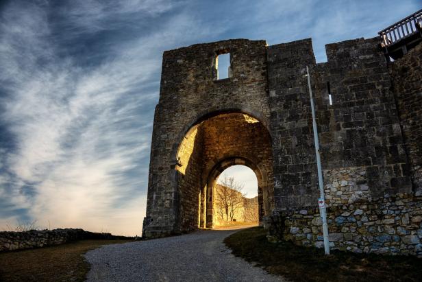 Ein Weg führt durch das Tor einer alten Burgruine.