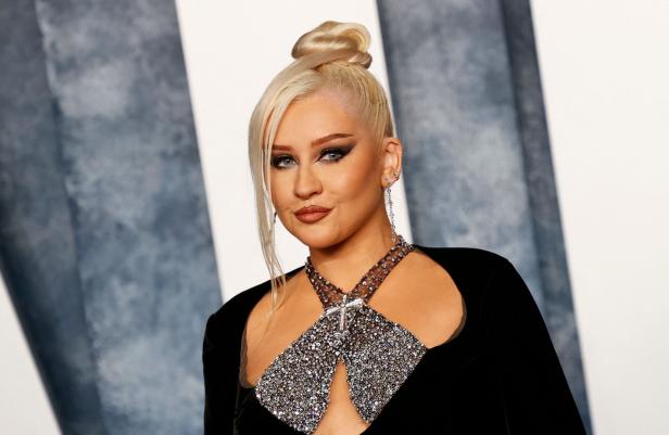Christina Aguilera mit blondem Dutt und schwarzem Kleid mit Strassapplikationen.