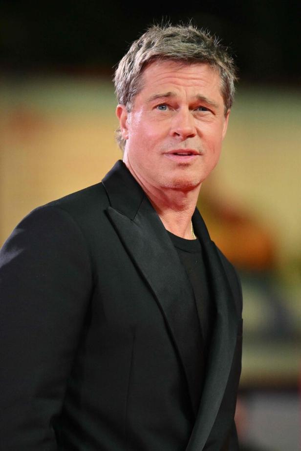 Brad Pitt in einem schwarzen Anzug auf einem roten Teppich.