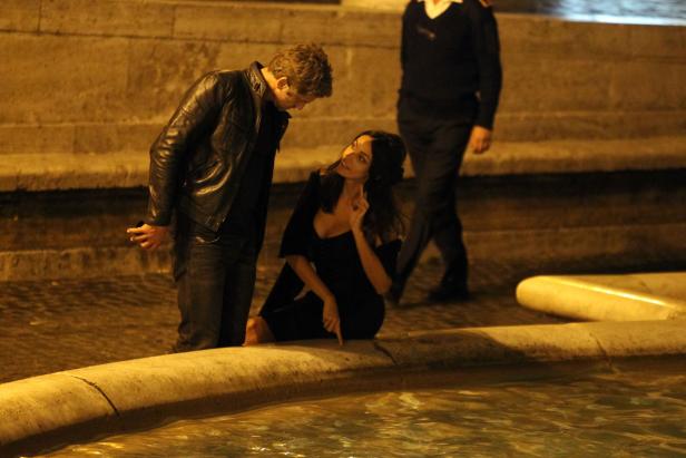 Ein Mann und eine Frau stehen nachts an einem Brunnen.