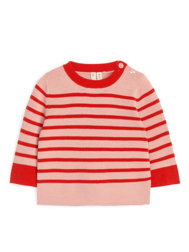 Ein rosa-rot gestreifter Kinderpullover liegt auf einem weißen Hintergrund.