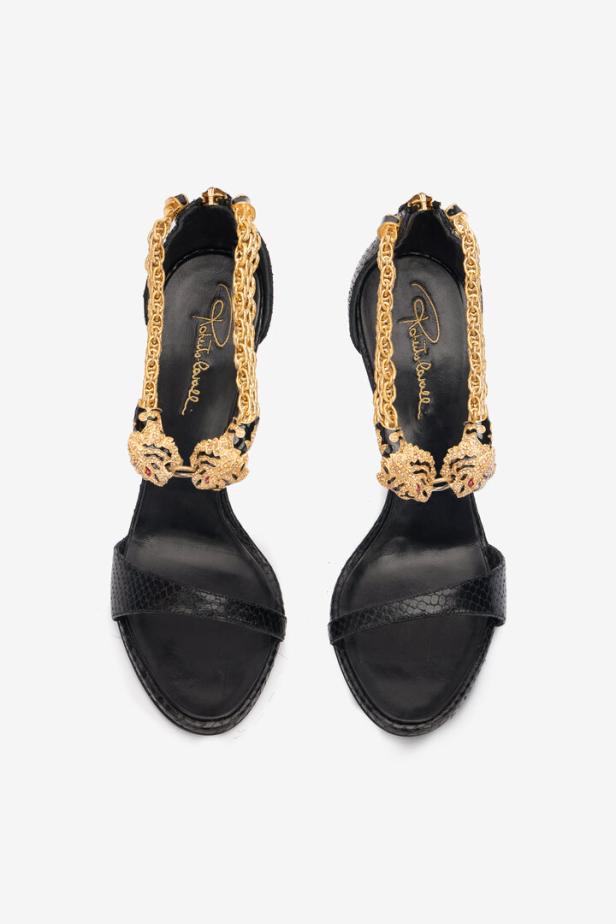Ein Paar schwarze High-Heel-Sandalen mit goldenen Ketten und Tigerkopf-Verzierungen.