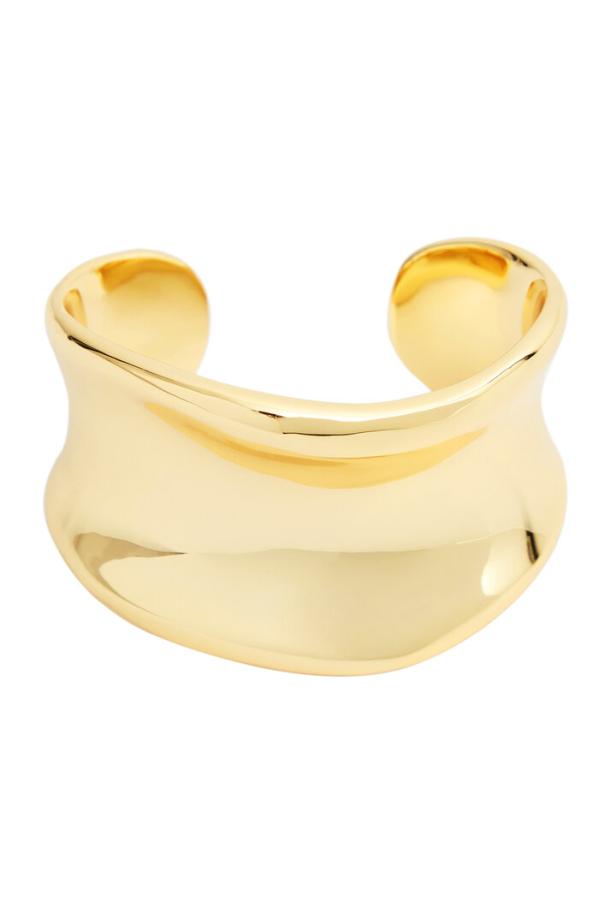 Ein breiter, goldener Armreif mit einer glänzenden Oberfläche.