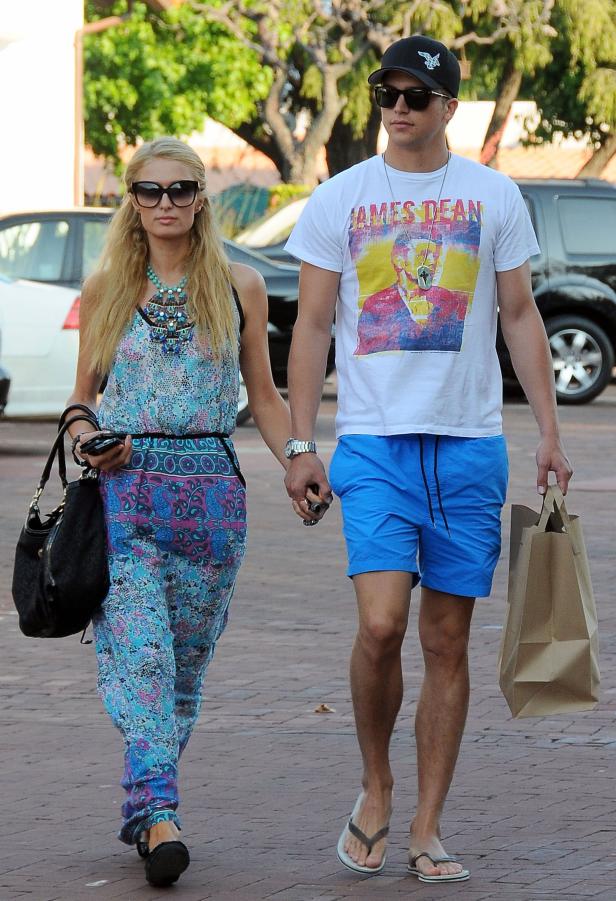 Paris Hilton und ein Mann mit einem James Dean T-Shirt gehen Händchen haltend die Straße entlang.