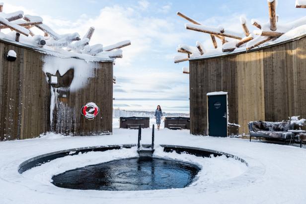 Eine Frau steht zwischen zwei Gebäuden mit Schnee und einem kleinen Pool im Winter.