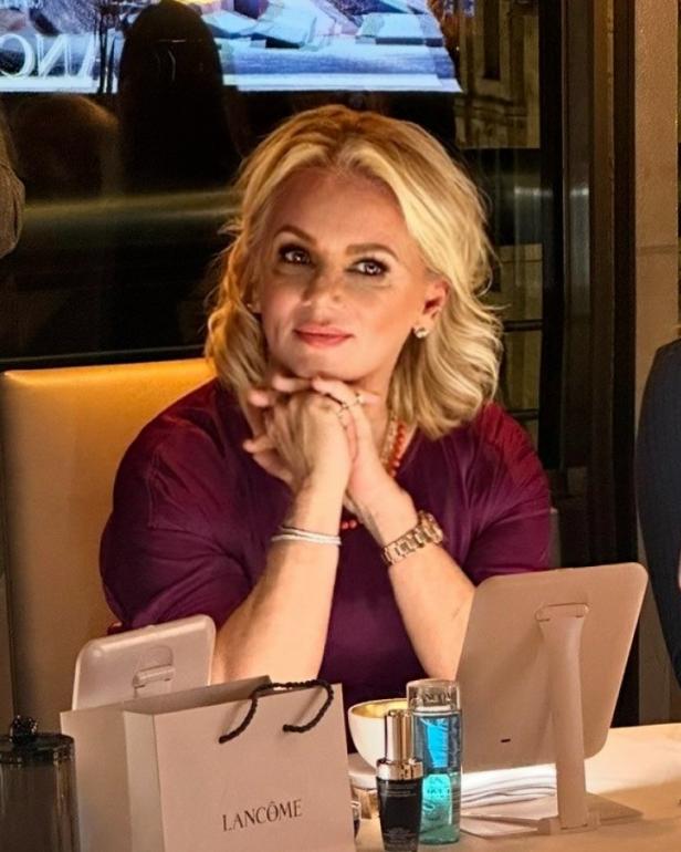 Eine blonde Frau sitzt an einem Tisch mit Lancôme-Produkten.