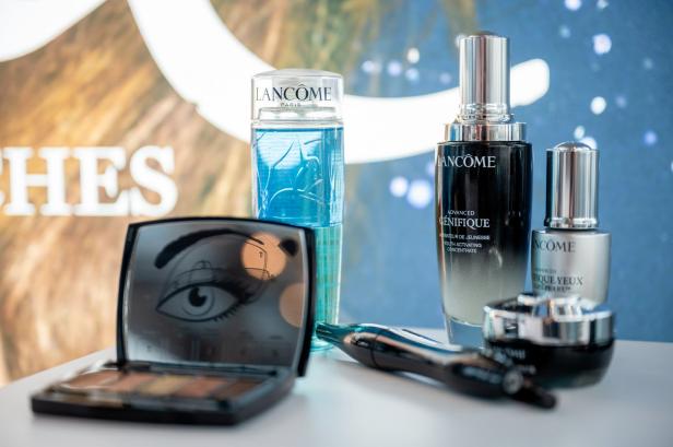 Verschiedene Lancôme-Kosmetikprodukte, darunter „Génifique“-Serum und Lidschatten, sind auf einem Tisch arrangiert.
