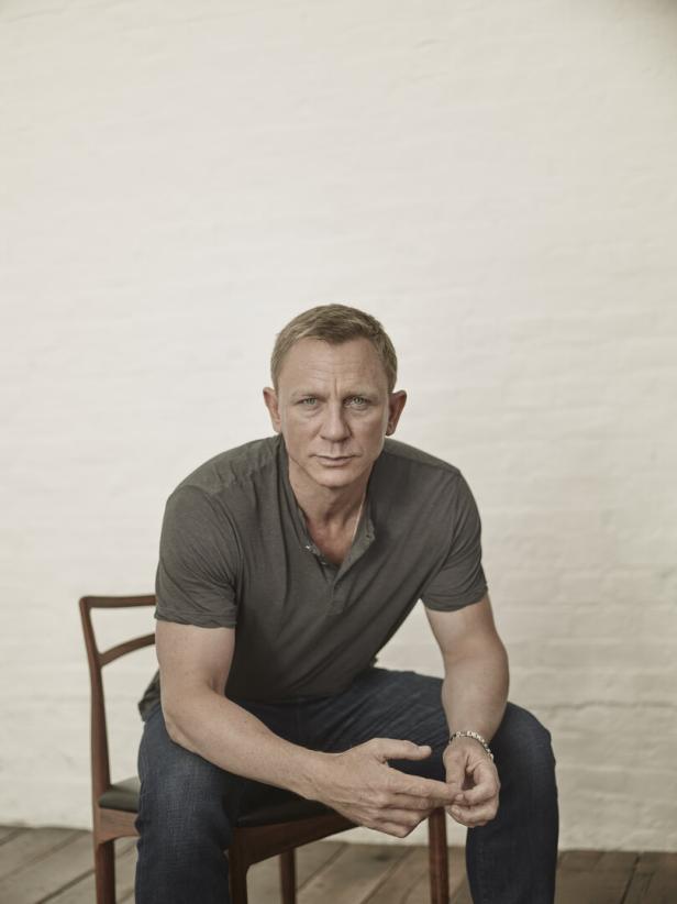 Daniel Craig sitzt auf einem Stuhl und blickt in die Kamera.