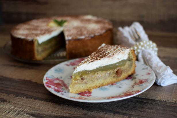 Ein Stück gedeckter Apfelkuchen mit Sahne und Kakao auf einem Teller.